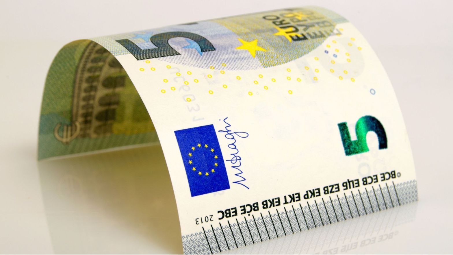 Un billete de cinco euros doblado en forma de puente.